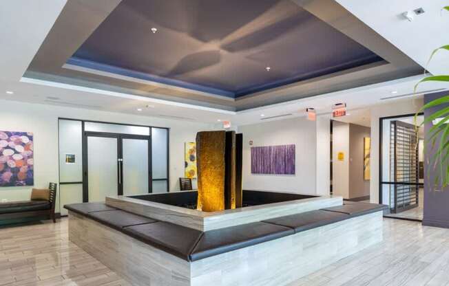 A modern lobby with a large artwork on the wall and a plant on the right.