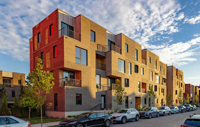 A row of modern apartment buildings with cars parked in front.