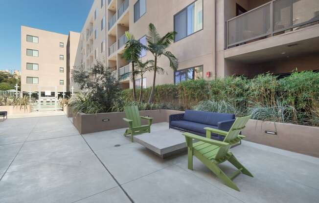 A patio with a couch, chairs and a table with a planter in between.