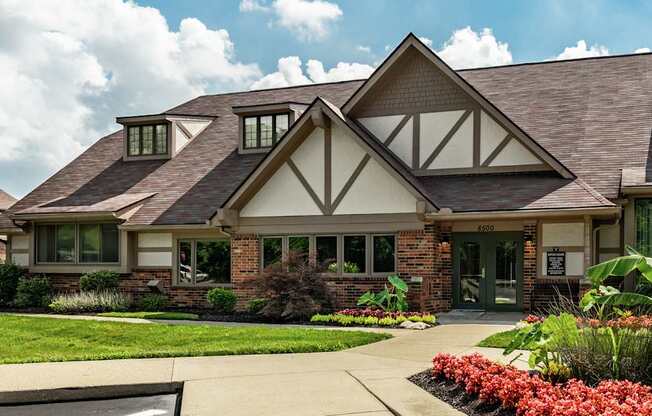 A house with a brown roof and white walls with a green lawn in front