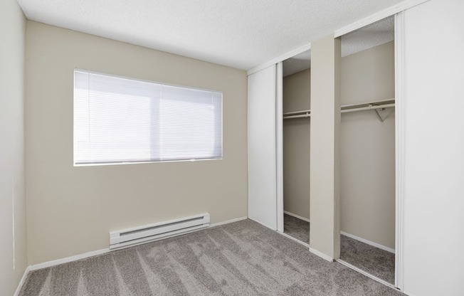 a bedroom with an empty closet and a large window