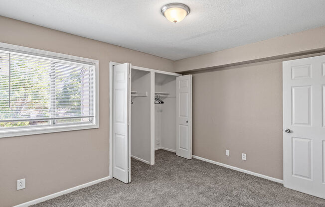 an empty bedroom with a window and a closet