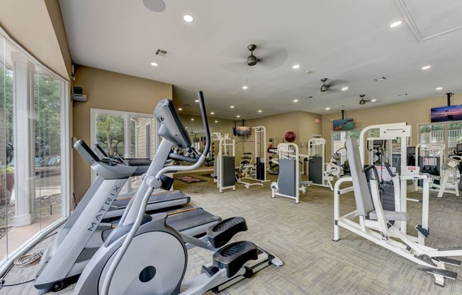 a gym with cardio equipment and glass doors