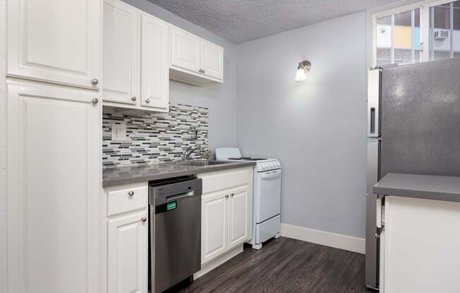 A kitchen with white cabinets and a black dishwasher.