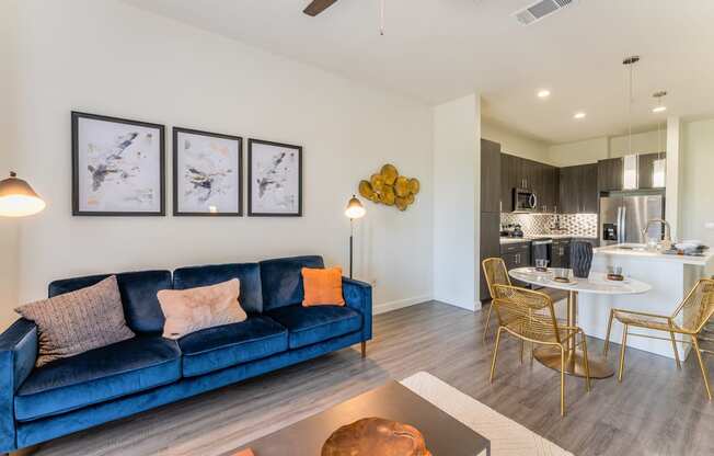 Living room with a blue couch and kitchen with wood flooring at Residences at 3000 Bardin Road, Texas