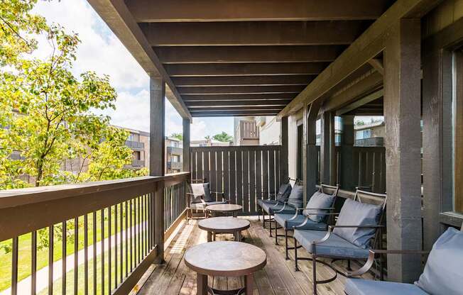 A wooden balcony with chairs and tables.