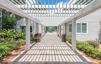 a pergola with a brick pathway in front of a house