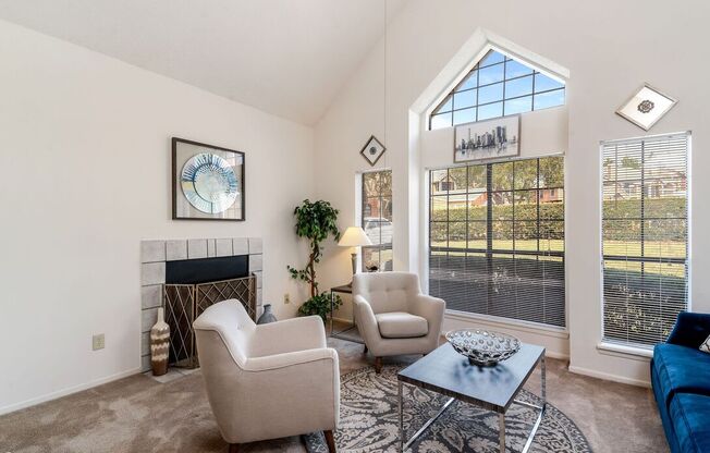 A living room with a fireplace, two chairs, and a coffee table.
