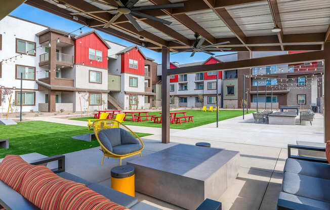A patio area with a yellow chair and a red couch.