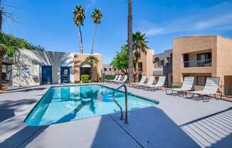 our resort style swimming pool is next to a building and palm trees
