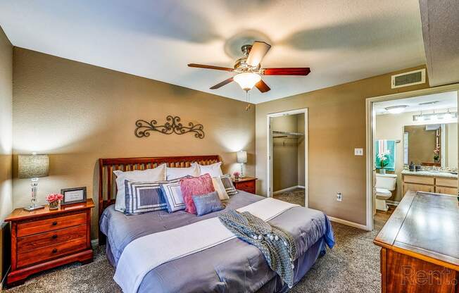 the master bedroom has a king sized bed and a ceiling fan