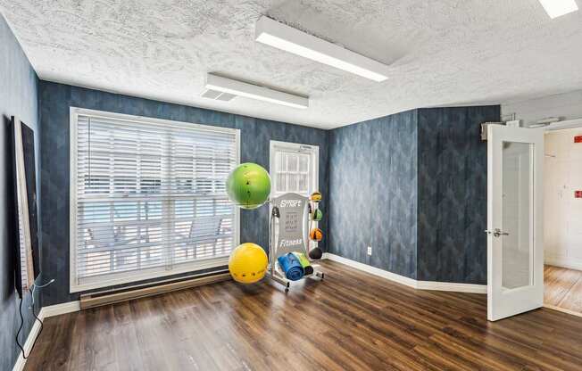 A room with a green ball hanging from the ceiling and a yellow ball on the floor.