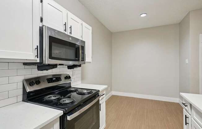 A kitchen with a stove, microwave, and cabinets.