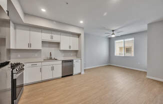 A modern kitchen with white cabinets and a wooden floor.