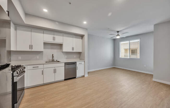A modern kitchen with white cabinets and a wooden floor.