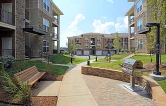 Exterior, grill, bench, three story apartments, sidewalk and some brick exterior.