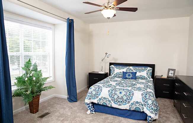 A bedroom with a bed, dresser, and ceiling fan.