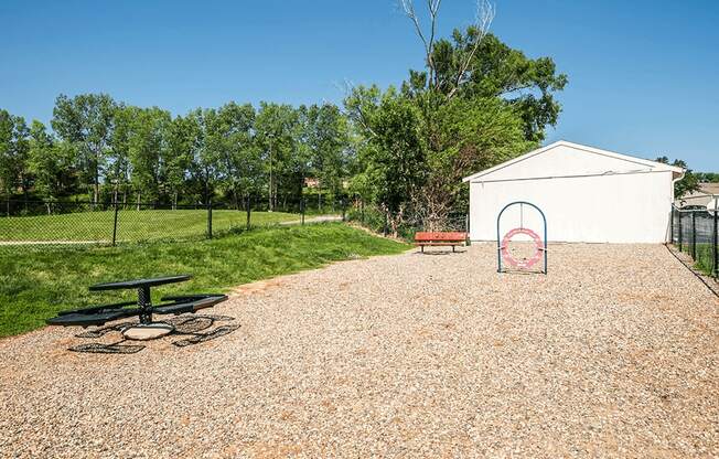 a gravel area with a picnic table and a bench in front of a white building