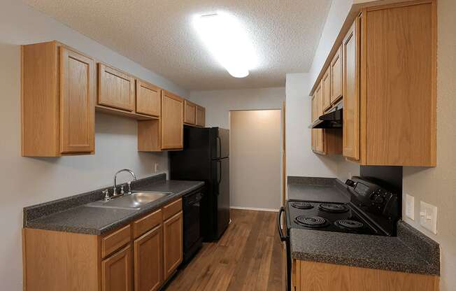 an empty kitchen with wood cabinets and a black stove and refrigerator
