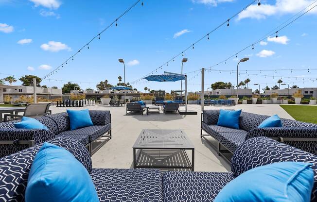 a seating area with blue couches and a table with blue pillows and a blue umbrella