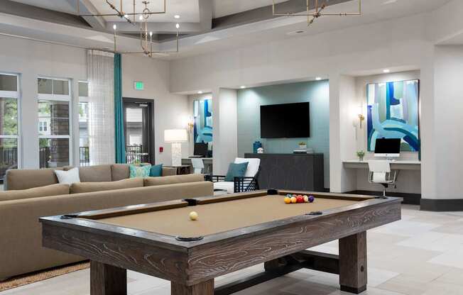 A pool table is in the middle of a room with a couch and a television.