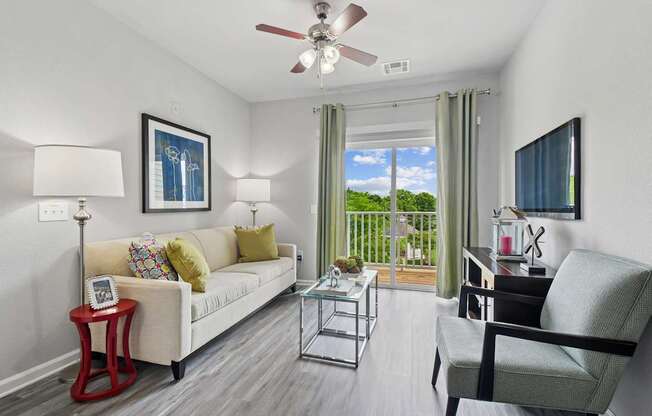 A living room with a white couch, a red side table, and a ceiling fan.