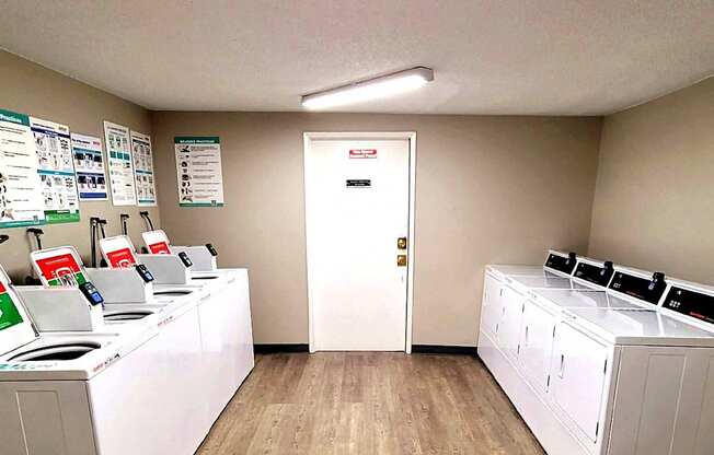 A laundromat with washers and dryers lined up on both sides of the room.