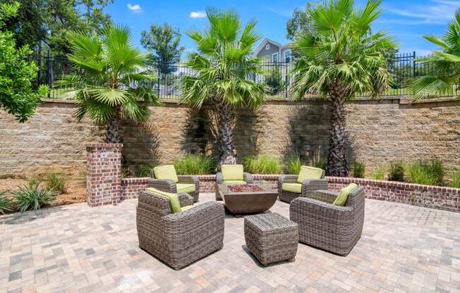 a patio with wicker furniture and a fire pit in front of a brick wall