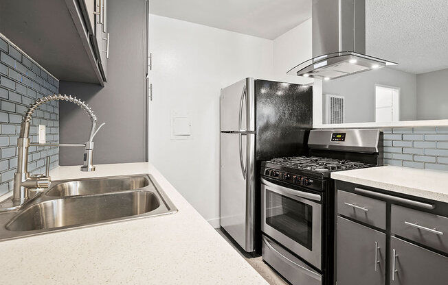 Blue tiled kitchen with stainless steel fridge, oven, and fixtures.