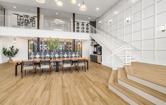 A white interior with a staircase and a long table with chairs.
