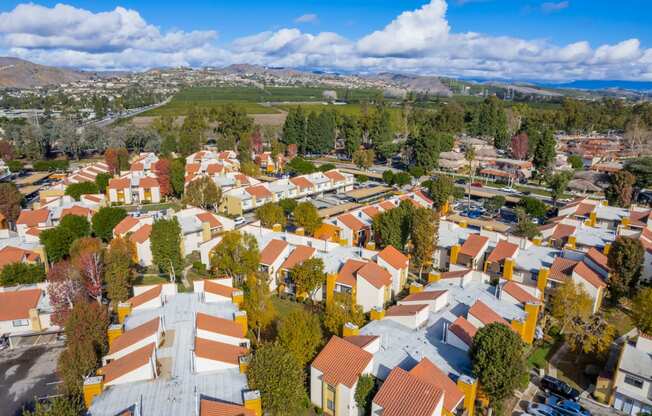 an aerial view of a neighborhood with orange roofs and a green hillside in the background
