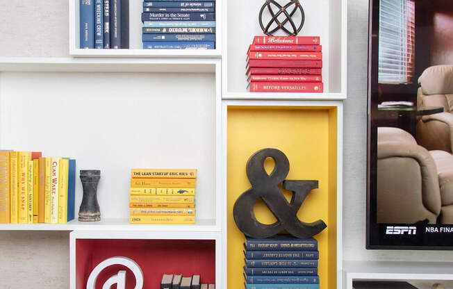 a bookshelf filled with books and a yellow bird on top at The Enclave, Jersey City, NJ