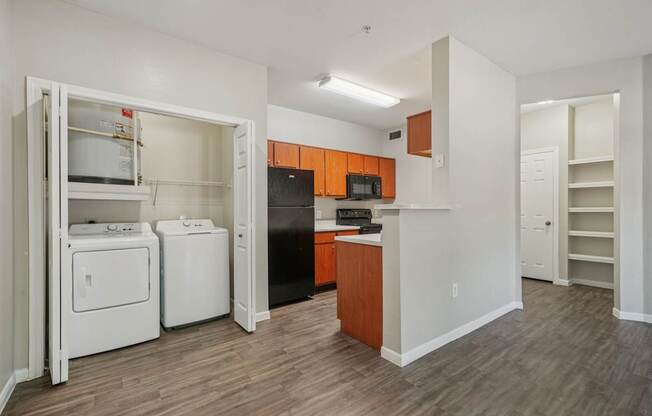 A kitchen with a black refrigerator, white oven, and white dishwasher.