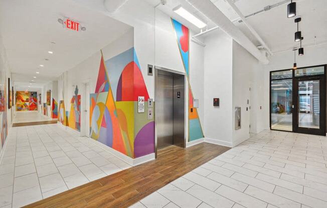 a hallway with a colorful mural on the wall and a door at Link Apartments® 4th Street, Winston-Salem