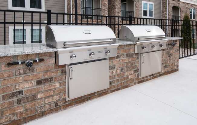 two barbecue grills on a brick wall in front of a house