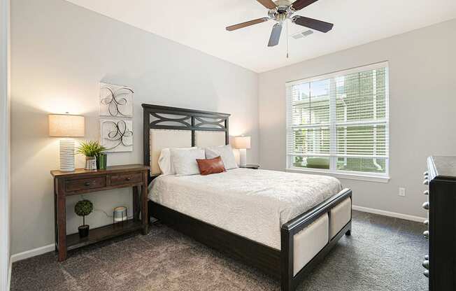 A bedroom with a bed, nightstand, and window.
