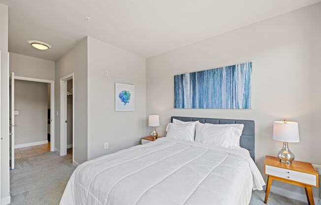 a bedroom with a large white bed and a blue painting on the wall