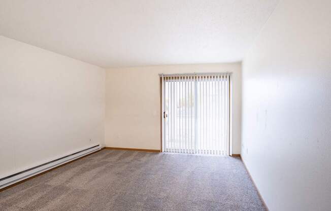 the spacious living room of an apartment with a door to the balcony. Fargo, ND Oxford Apartments