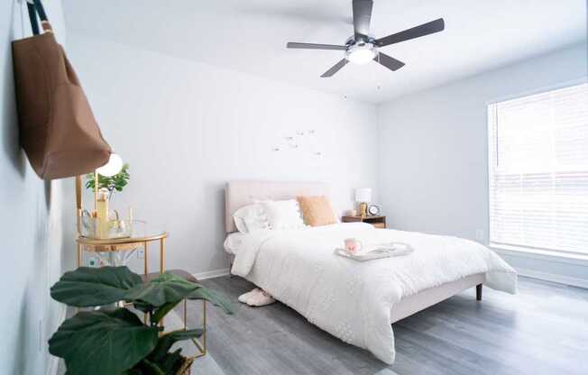 a white bedroom with a bed and a ceiling fan