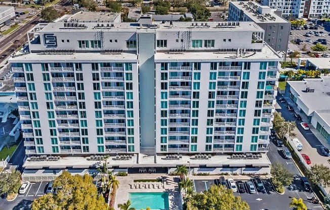 A large white hotel with a pool in the middle.