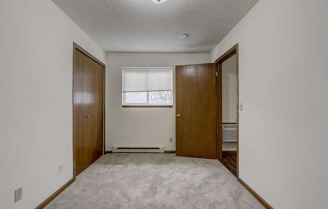 an empty room with a door to a closet and a window