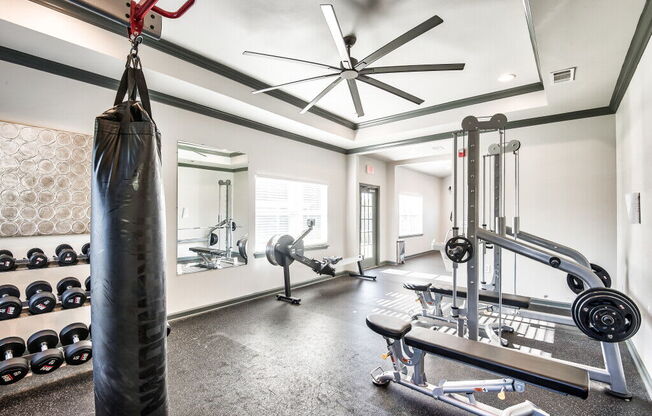A gym with a punching bag, weights, and a ceiling fan.