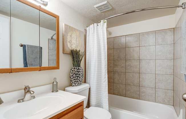 Bright bathroom with tile surround and decorative mirror in pet-friendly Aurora unit.