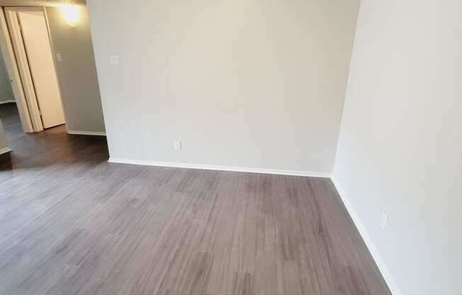 an empty living room with wood floors and a ceiling fan