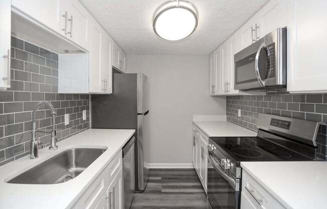 A kitchen with white cabinets and a black refrigerator.