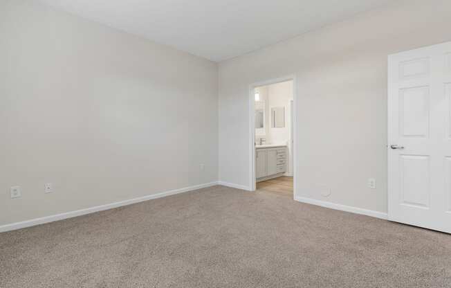 a bedroom with carpet and a door to a bathroom
