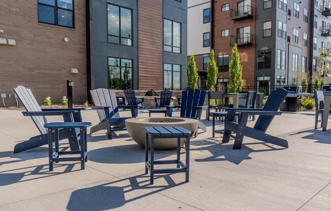 A patio with chairs and tables is surrounded by buildings.