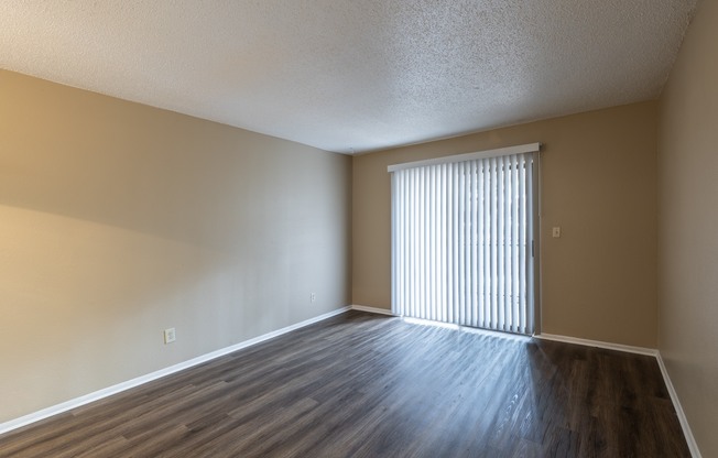 A room with wooden floors and a window with blinds.