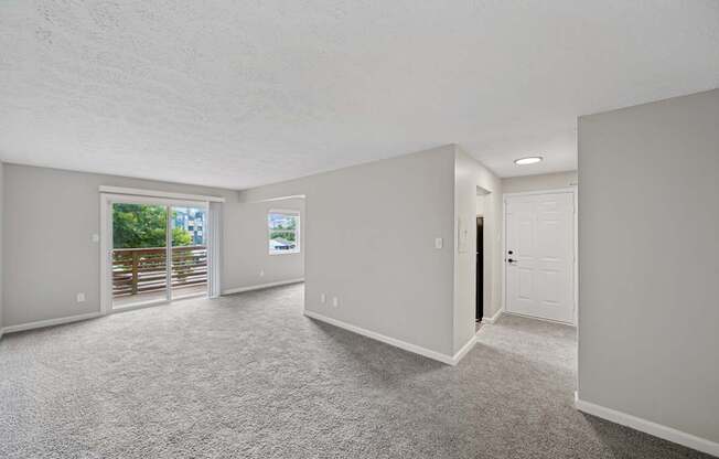 A spacious room with a carpeted floor and a door on the right side.