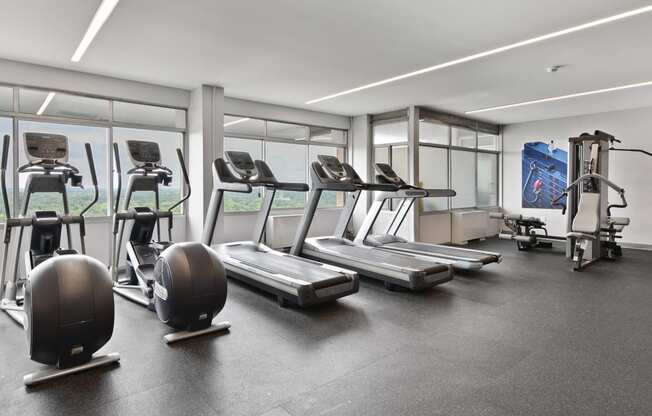 a gym with treadmills and other exercise equipment in a building with windows